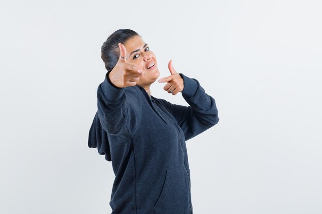 Young lady pointing at camera in jacket and looking energetic 