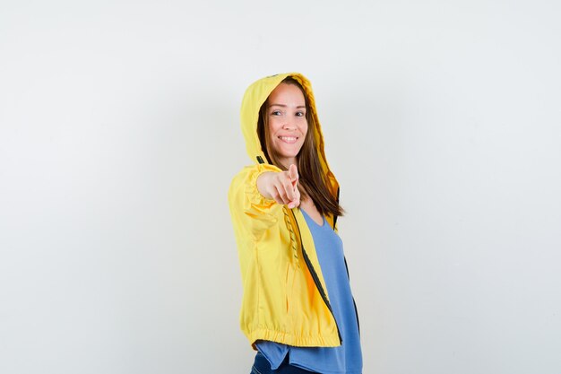 Young lady pointing at camera in t-shirt, jacket and looking confident , front view.