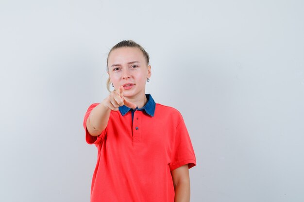 Young lady pointing at front in t-shirt and looking confident