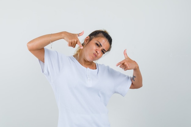 Young lady pointing at herself in t-shirt and looking proud 
