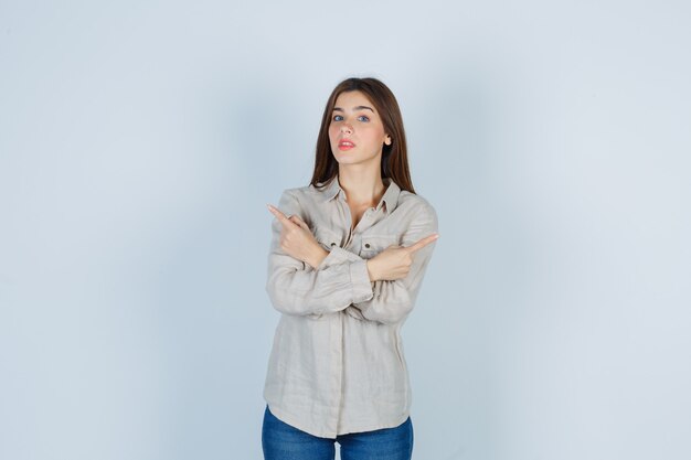 Young lady pointing to the left and right sides in casual, jeans and looking surprised. front view.