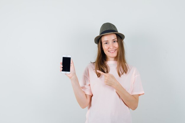 Девушка в розовой футболке, указывая на мобильный телефон и радостно глядя
