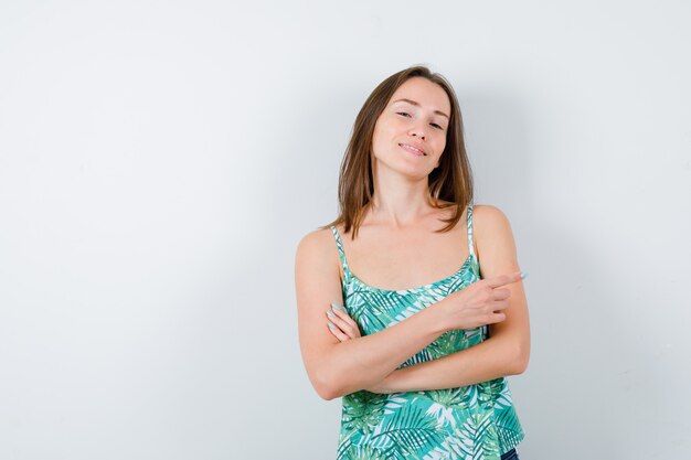 Young lady pointing right and looking relaxed , front view.