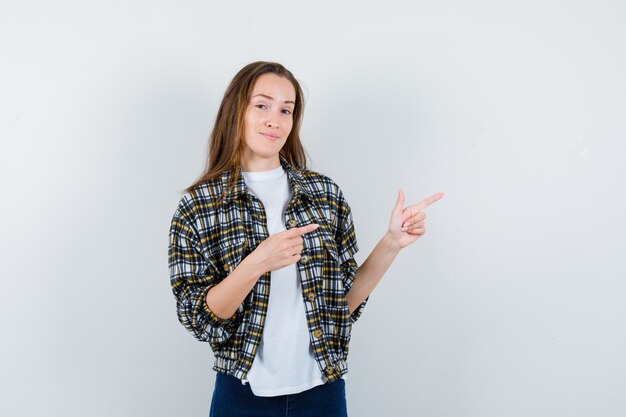 Foto gratuita giovane donna che punta a destra in t-shirt, giacca, jeans e sembra sicura di sé. vista frontale.