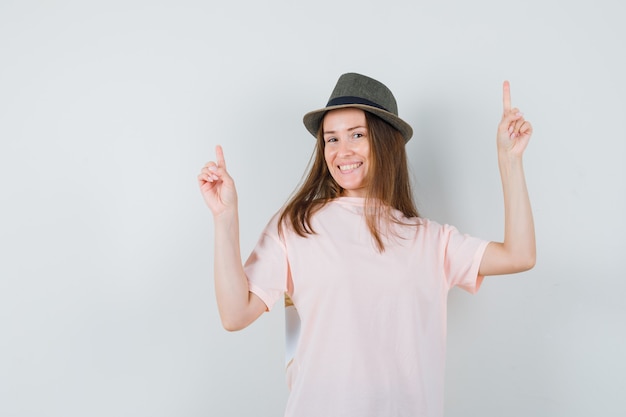 Young lady pointing up in pink t-shirt hat and looking cheerful  