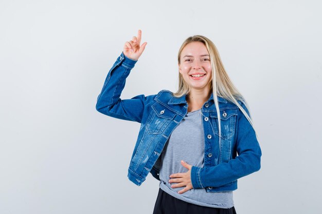 Tシャツ、デニムジャケット、スカートで上向きで魅力的な若い女性