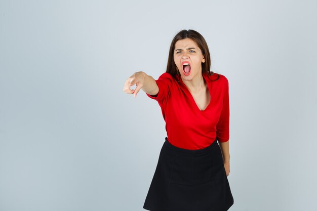 Young lady pointingwith index finger in red blouse