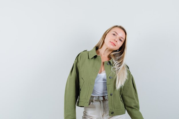 Young lady posing while standing in jacket, pants and looking captivating. front view.