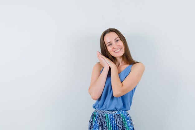 Young lady posing while standing in singlet, skirt and looking happy. front view.