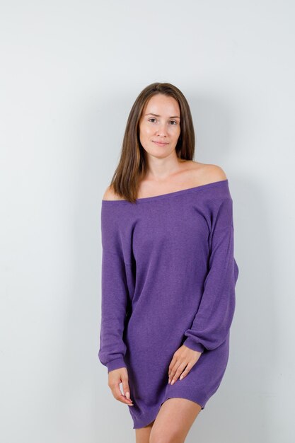 Young lady posing while standing in violet shirt and looking fascinating. front view.