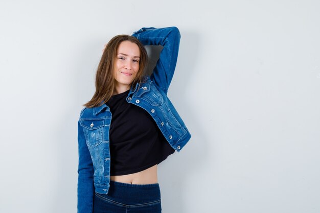 Young lady posing with hand on head in blouse and looking graceful , front view.