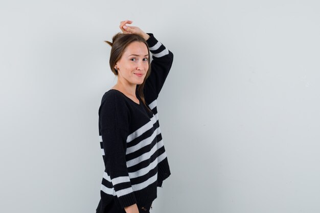 Young lady posing with hand on head in shirt and looking elegant