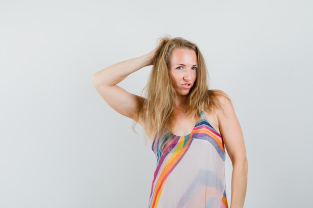 Young lady posing with hand behind head in summer dress and looking elegant. 