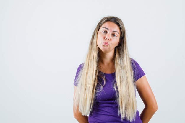 Young lady pouting lips in violet t-shirt and looking cute. front view.