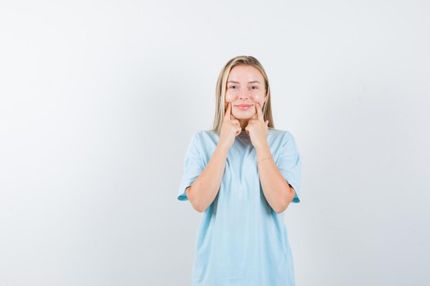 Young lady pressing fingers on cheeks in t-shirt and looking cute isolated