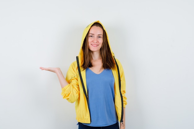 Young lady pretending to hold or show something in her hand and looking confident. front view.