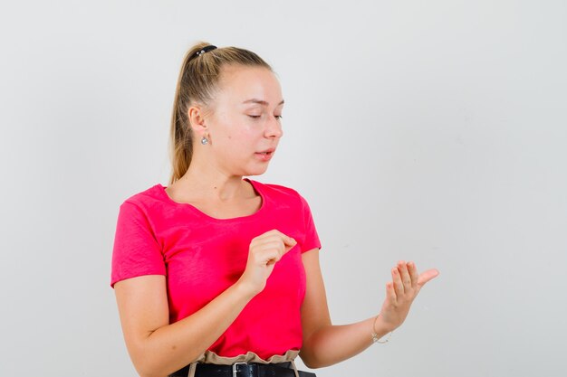 Young lady pretending to hold something in t-shirt and looking focused
