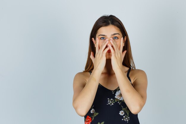 Young lady pretending to rub face mask on around nose zone in blouse and looking charming. front view.