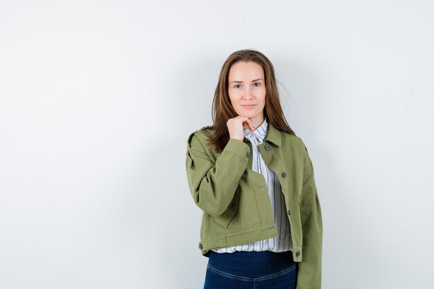 Young lady propping chin on hand in blouse and looking sensible.