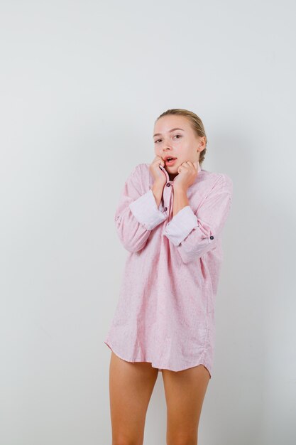 Young lady pulling collar in pink shirt and looking cute