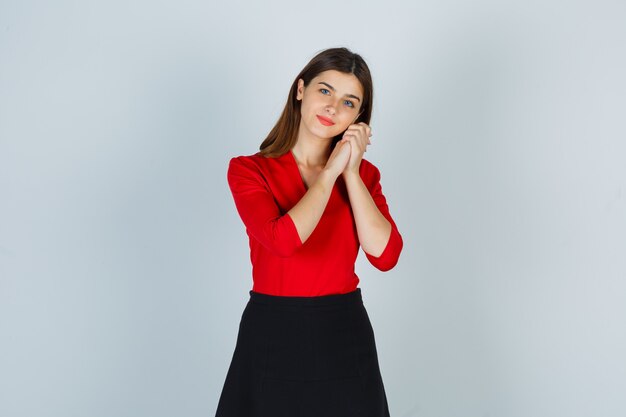 Young lady in red blouse, skirt leaning on hands as pillow and looking pleased