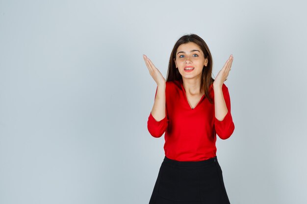 Young lady in red blouse, skirt playing peek a boo and looking cute