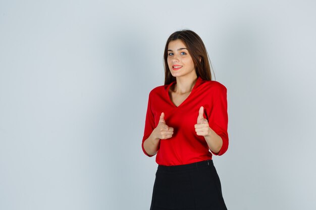 Young lady in red blouse, skirt pointing at camera and looking gorgeous