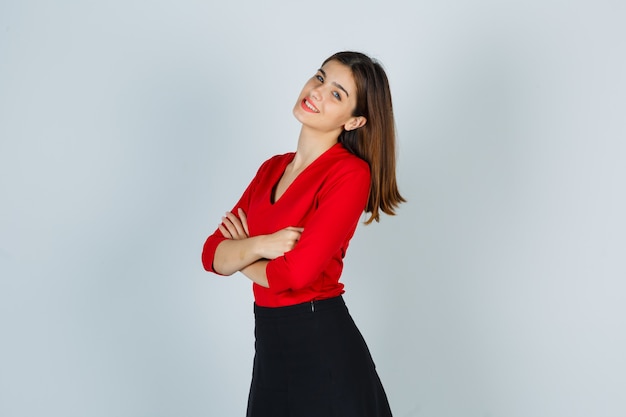 Youthful Woman in Vibrant Blouse and Skirt Poses Joyfully with Arms Crossed