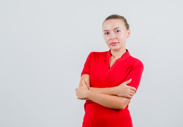 自分を抱き締めて陽気に見える赤いTシャツの若い女性