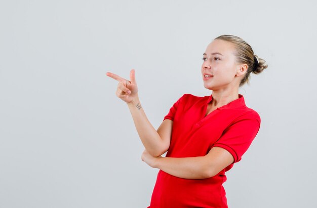 赤いTシャツを着た若い女性が何かを指差して陽気に見える