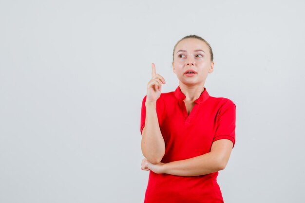 Young lady in red t-shirt pointing up and looking focused