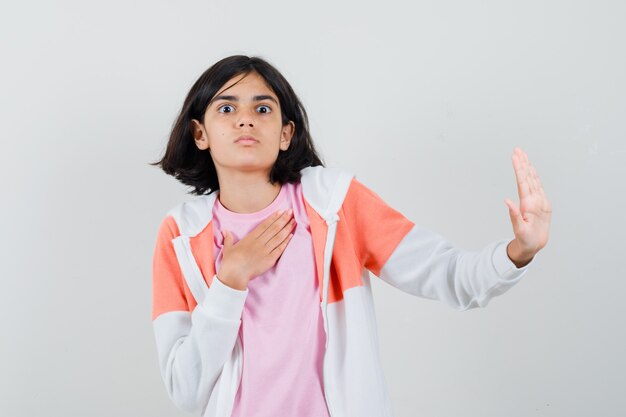 Young lady rejecting something in jacket, pink shirt and looking reluctant.