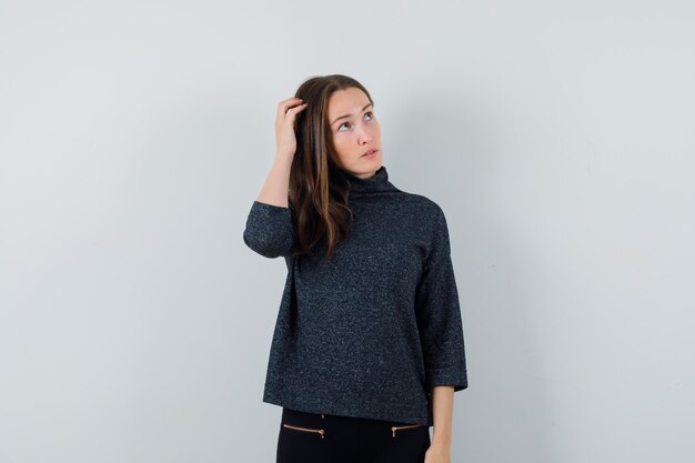 Young lady scratching head in shirt