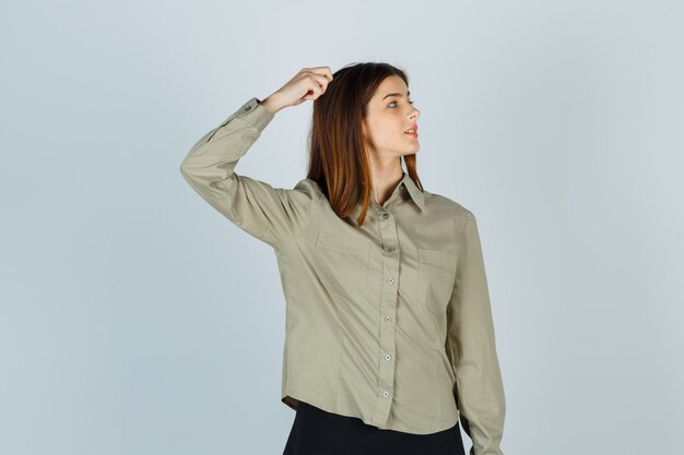 Young lady scratching head while looking aside in shirt, skirt and looking focused. front view.