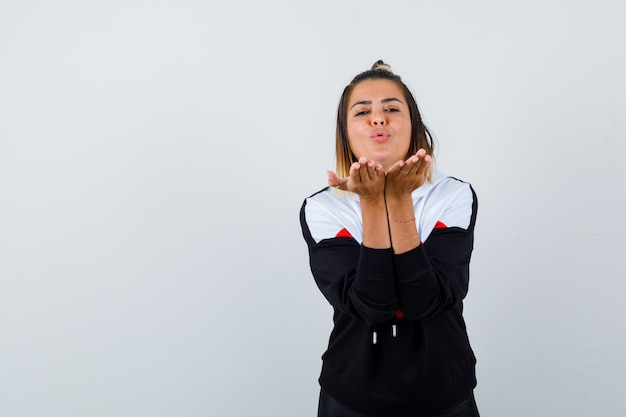 Young lady sending air kiss in hoodie sweater and looking pretty.
