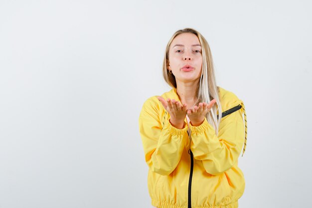 Young lady sending kiss with hand in t-shirt, jacket and looking cute
