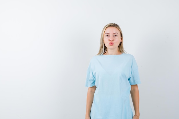 Young lady sending kiss with pouting lips in t-shirt and looking cute