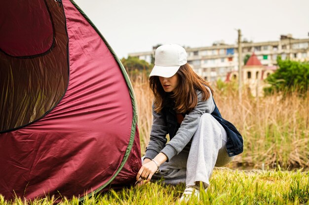 A young lady setting up her tent at the forest