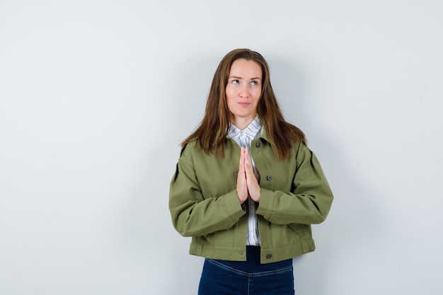 Free photo young lady in shirt, jacket showing namaste gesture and looking dreamy , front view.