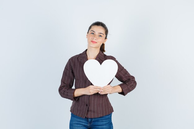 Young lady in shirt, jeans keeping paper poster and looking lovely , front view.