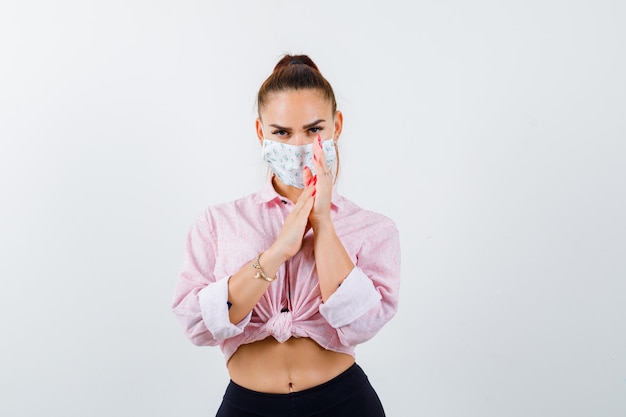 Young lady in shirt, mask rubbing palms together and looking sensible , front view.