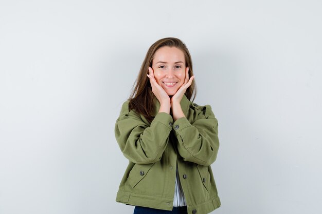 Young lady in shirt pillowing face on her hands and looking pretty , front view.