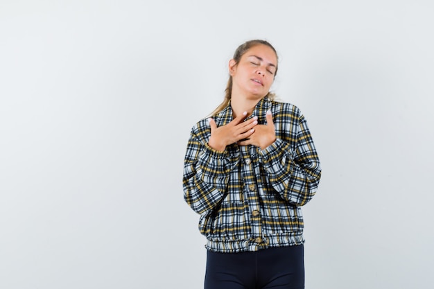 Free photo young lady in shirt, shorts holding hands on chest and looking grateful , front view.