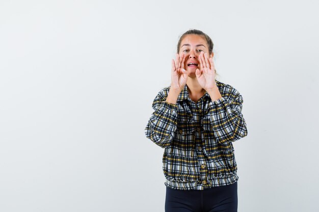 Young lady in shirt, shorts shouting or announcing something , front view.