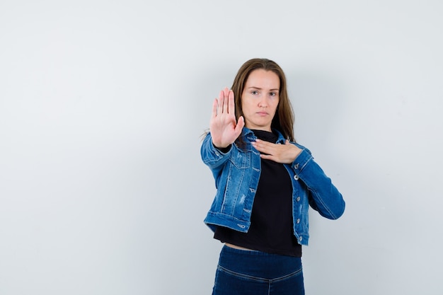 Foto gratuita giovane donna in camicia che mostra il gesto di arresto e sembra sicura, vista frontale.