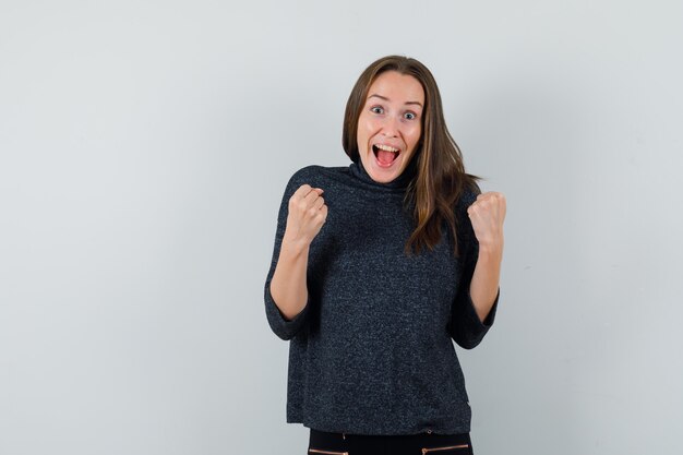 Young lady in shirt showing winner gesture and looking crazy