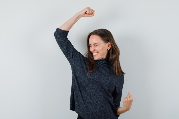 Young lady in shirt showing winner gesture and looking lucky