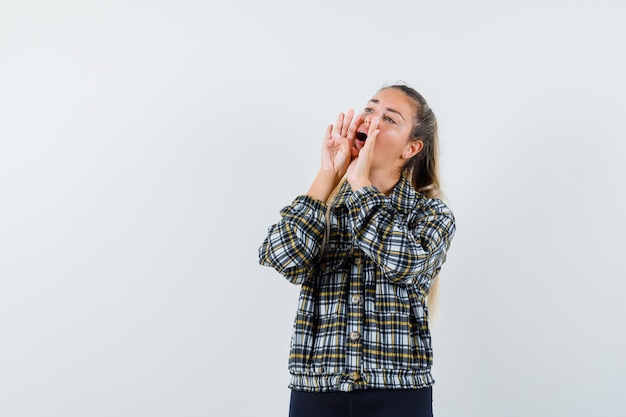 Young lady shouting or announcing something in checked shirt front view.