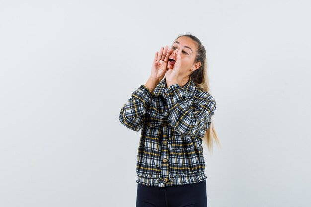 Young lady shouting or announcing something in shirt, shorts , front view.