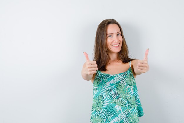 Young lady showing double thumbs up and looking happy. front view.